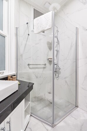 Suite estudio junior, 1 habitación, para no fumadores, vista a la ciudad | Baño | Regadera, regadera tipo lluvia, secadora de cabello, pantuflas 