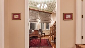 A hallway with a patterned rug, wooden stairs, and a dining area with a chandelier. - White Palace Old City Boutique Hotel (Istanbul)