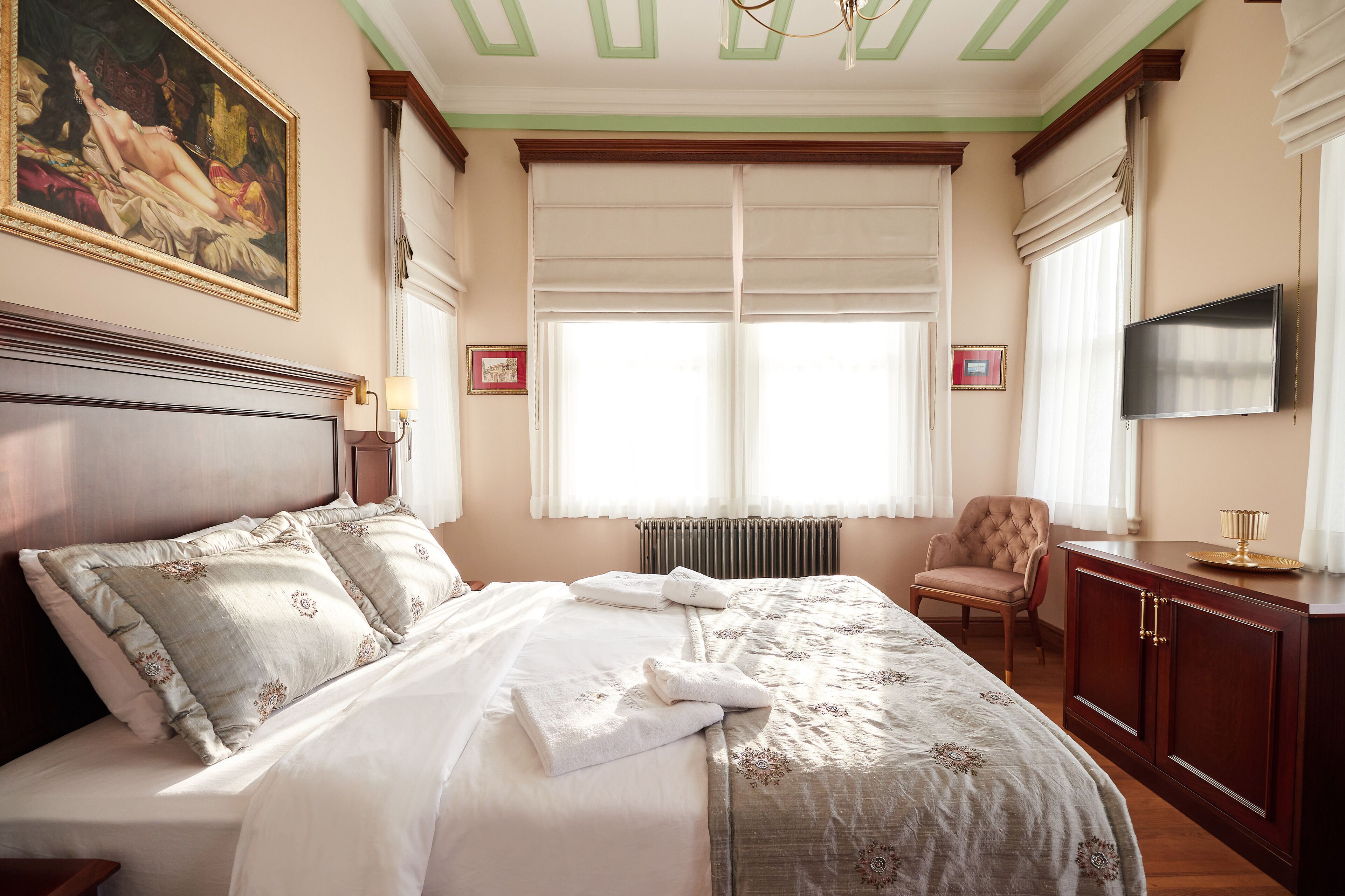 A well-appointed hotel room with a large bed, a television, a chair, and a cabinet.