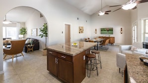 A spacious kitchen with a central island, a dining area with a long table, and a living room with a sofa and a TV. - Scottsdale Family Escape: Golf, Pool and Spa (Scottsdale)