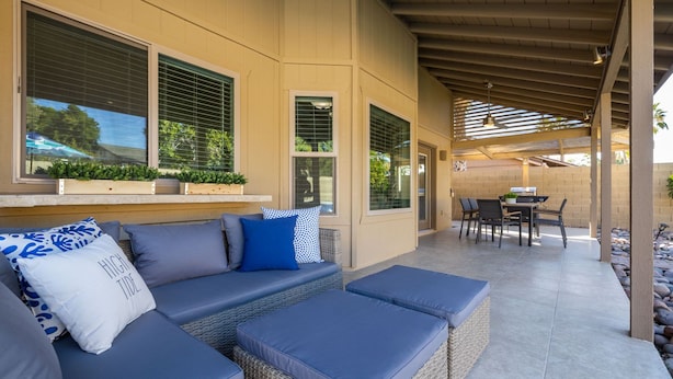 A covered patio area with a sofa and ottoman, a table with chairs, and a grill. - Scottsdale Family Escape: Golf, Pool and Spa (Scottsdale)