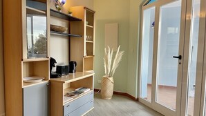 A compact room with a built-in kitchenette, a small seating area, and a sliding glass door leading to an outdoor area. - Apartment 6 pers 3 mn from the beach sea view (FAVONE)