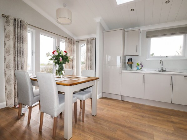 Una cocina moderna con armarios blancos, una mesa de comedor de madera y un jarrón con flores.