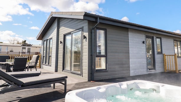 A modern house with a hot tub, deck, and outdoor furniture. - Acorn Lodge (Redruth)