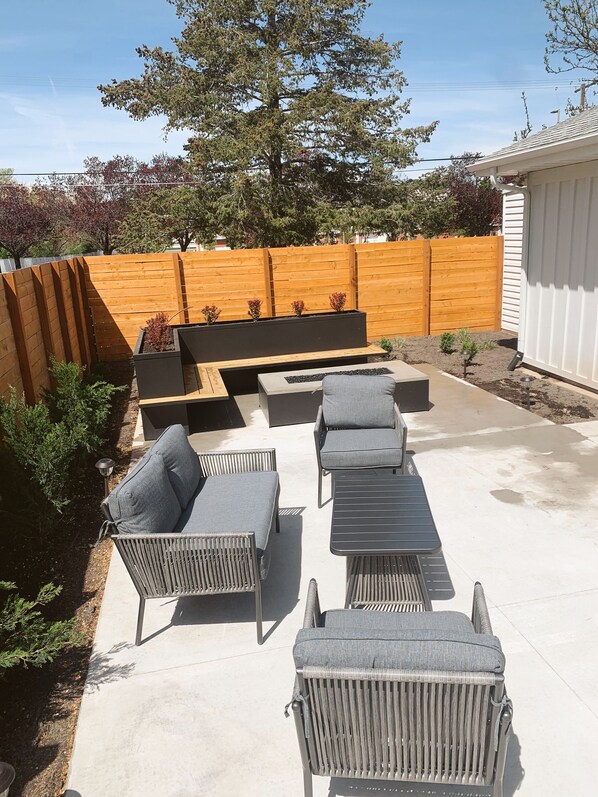 A patio area with outdoor furniture, including a sofa and chairs, a small table, and a planter with plants.