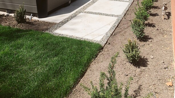 Een achtertuin met een jacuzzi, buitenzitplaatsen, een stenen openhaard en een tuin met kleine planten.