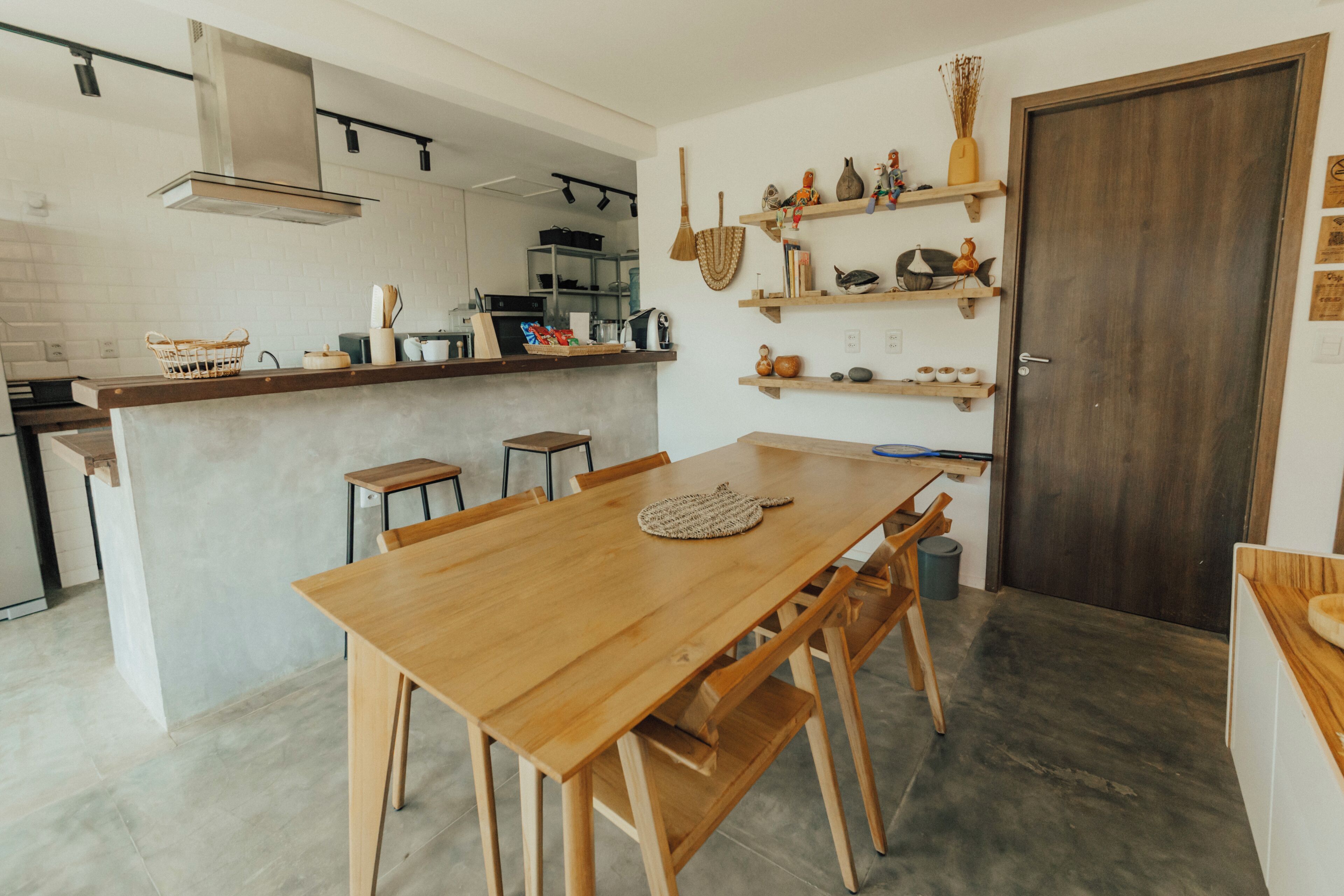 A modern kitchen with a wooden dining table, chairs, and a built-in island with bar stools.
