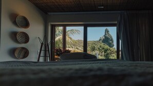 A bedroom with a large window, a bed, and a view of a mountain.