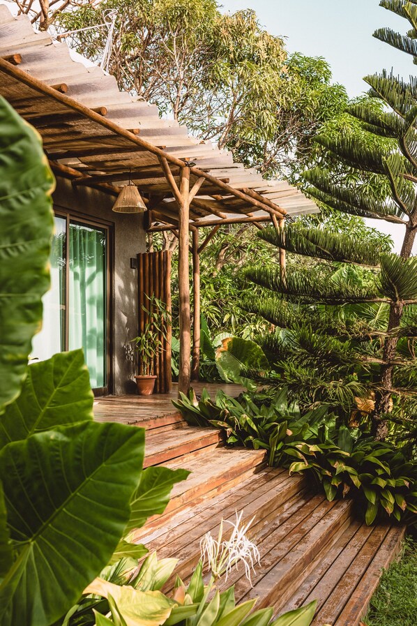Une terrasse en bois agrémentée d’une végétation luxuriante et surmontée d’une pergola.