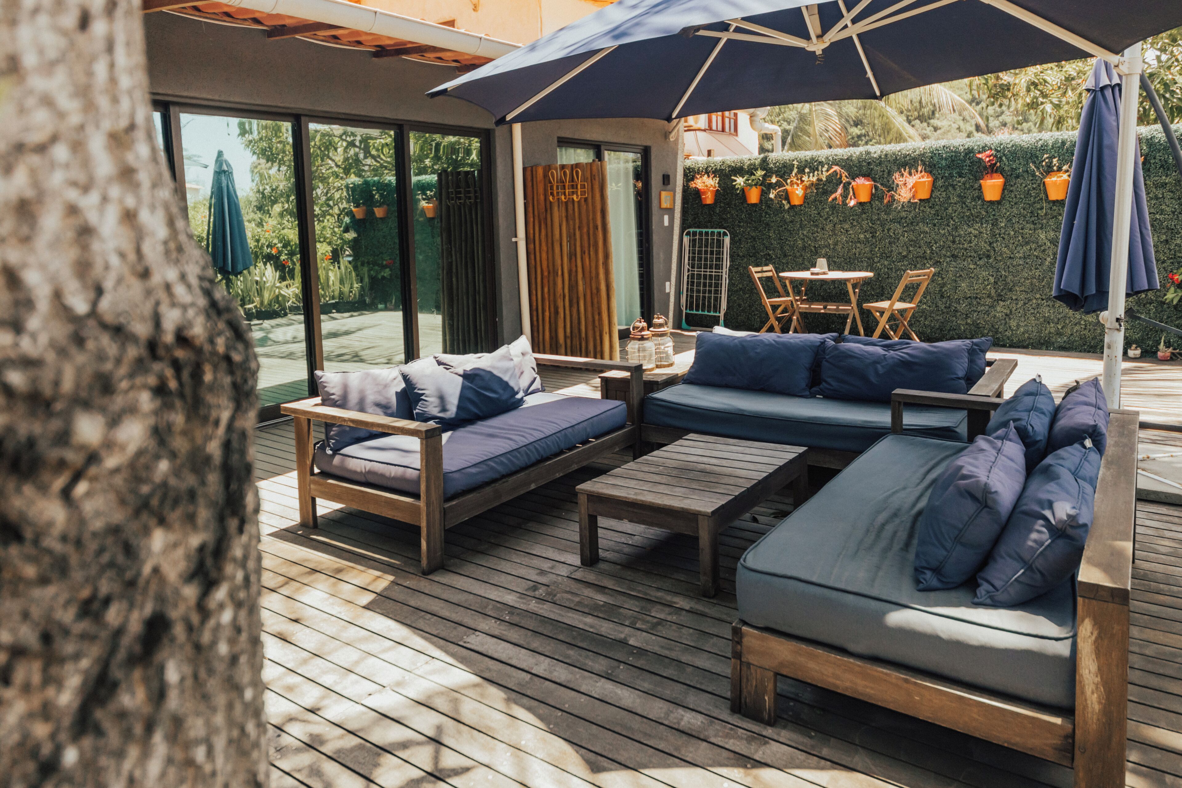 A wooden deck with a sofa, two chairs, and a table.