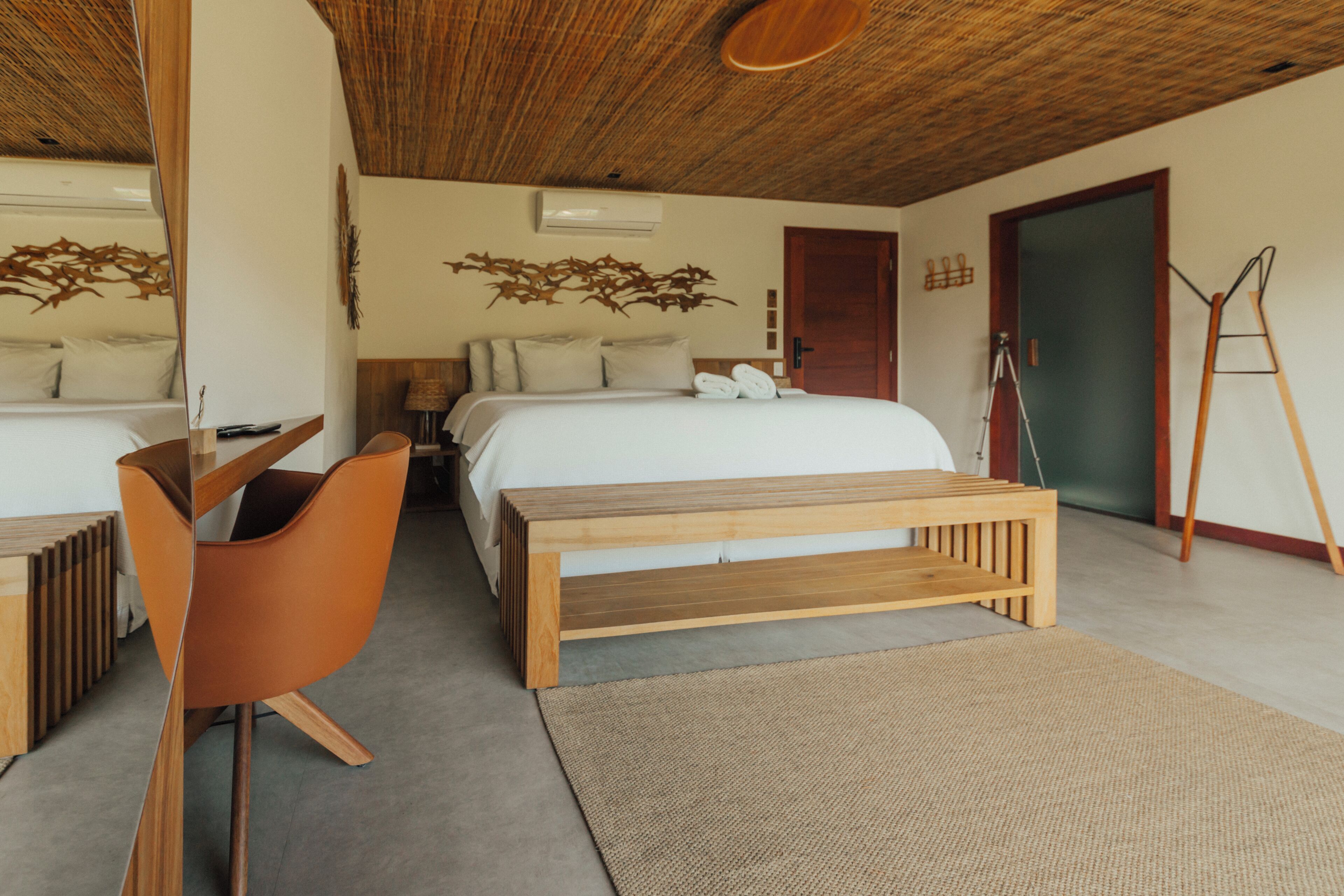 A bedroom with a bed, a wooden bench, a chair, a desk, and a ladder.