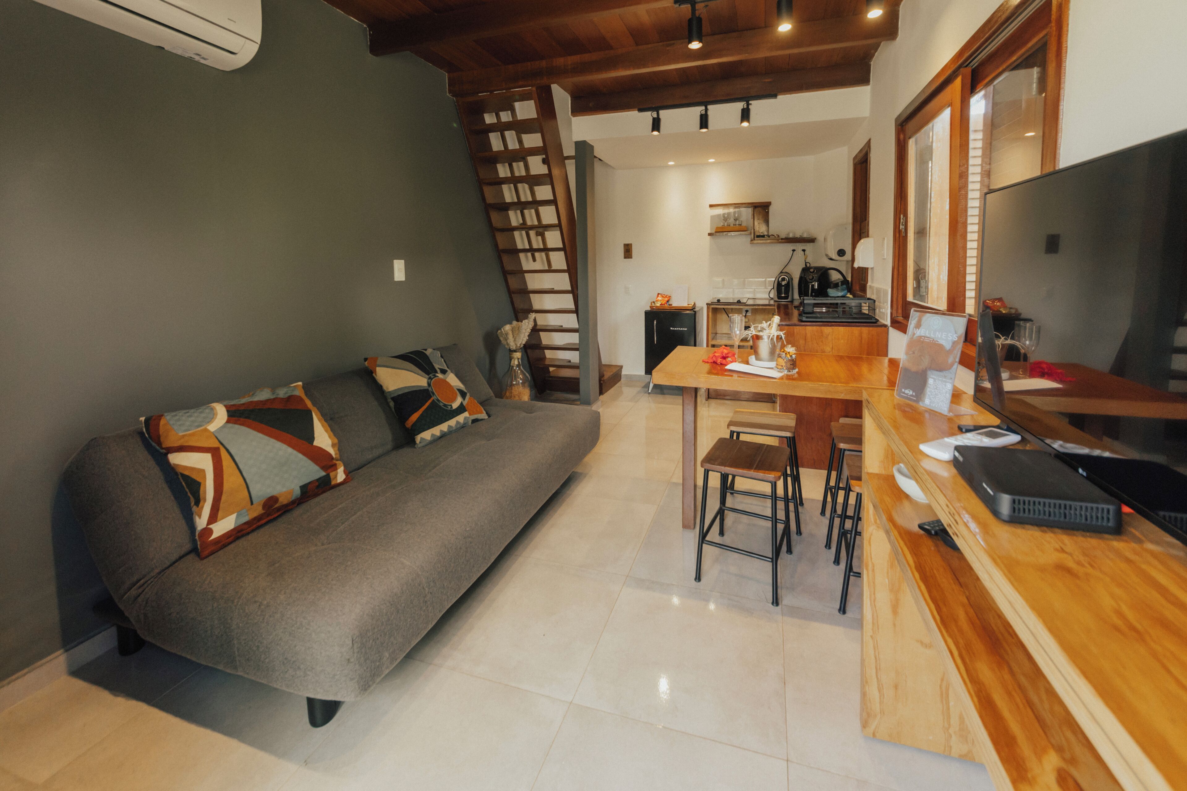 A modern living room with a sofa, a wooden dining table, and a kitchen in the background.