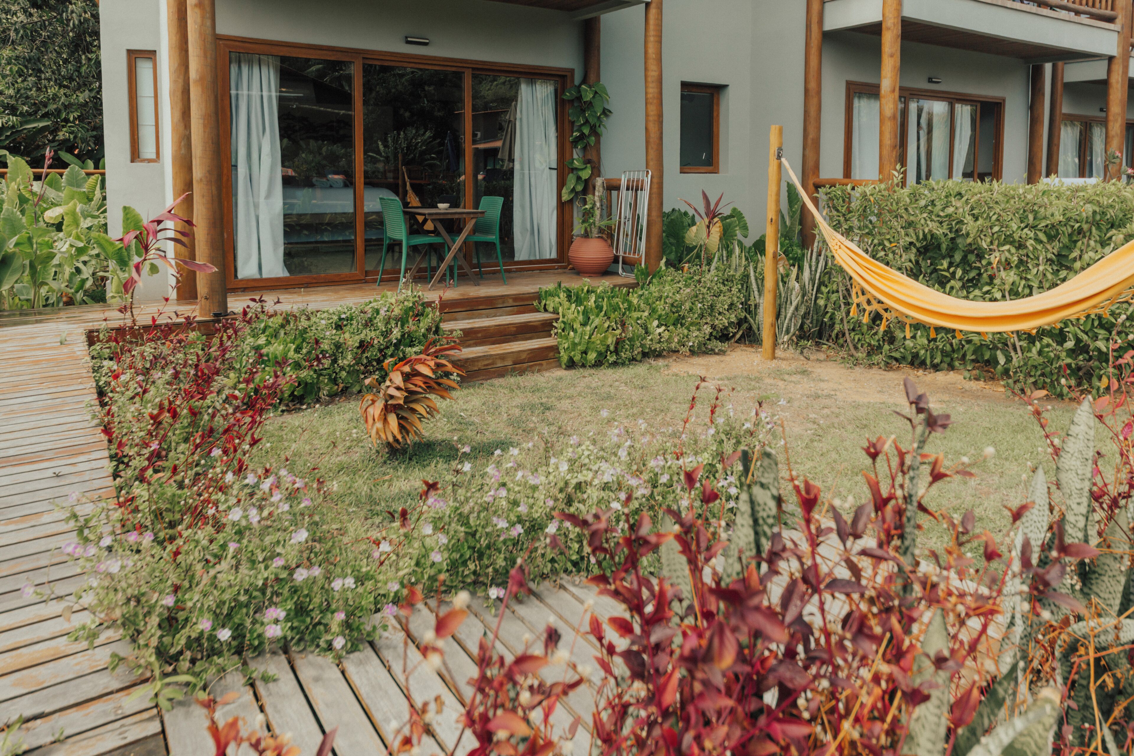 A wooden deck with a hammock, a dining area with chairs, and a large sliding glass door.