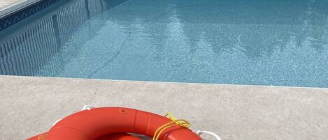 A swimming pool with a lifebuoy and ropes on the deck.