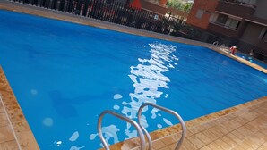 Une piscine avec une eau d’un bleu limpide et une échelle métallique qui y mène.