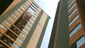 Un immeuble de grande hauteur doté d’une architecture moderne, caractérisé par des lignes verticales et une combinaison de façades en brique et en verre.