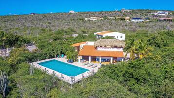 A large house with a swimming pool surrounded by lush greenery.