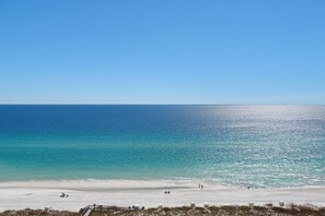 Une plage avec un ciel dégagé, une mer calme et un rivage sablonneux.
