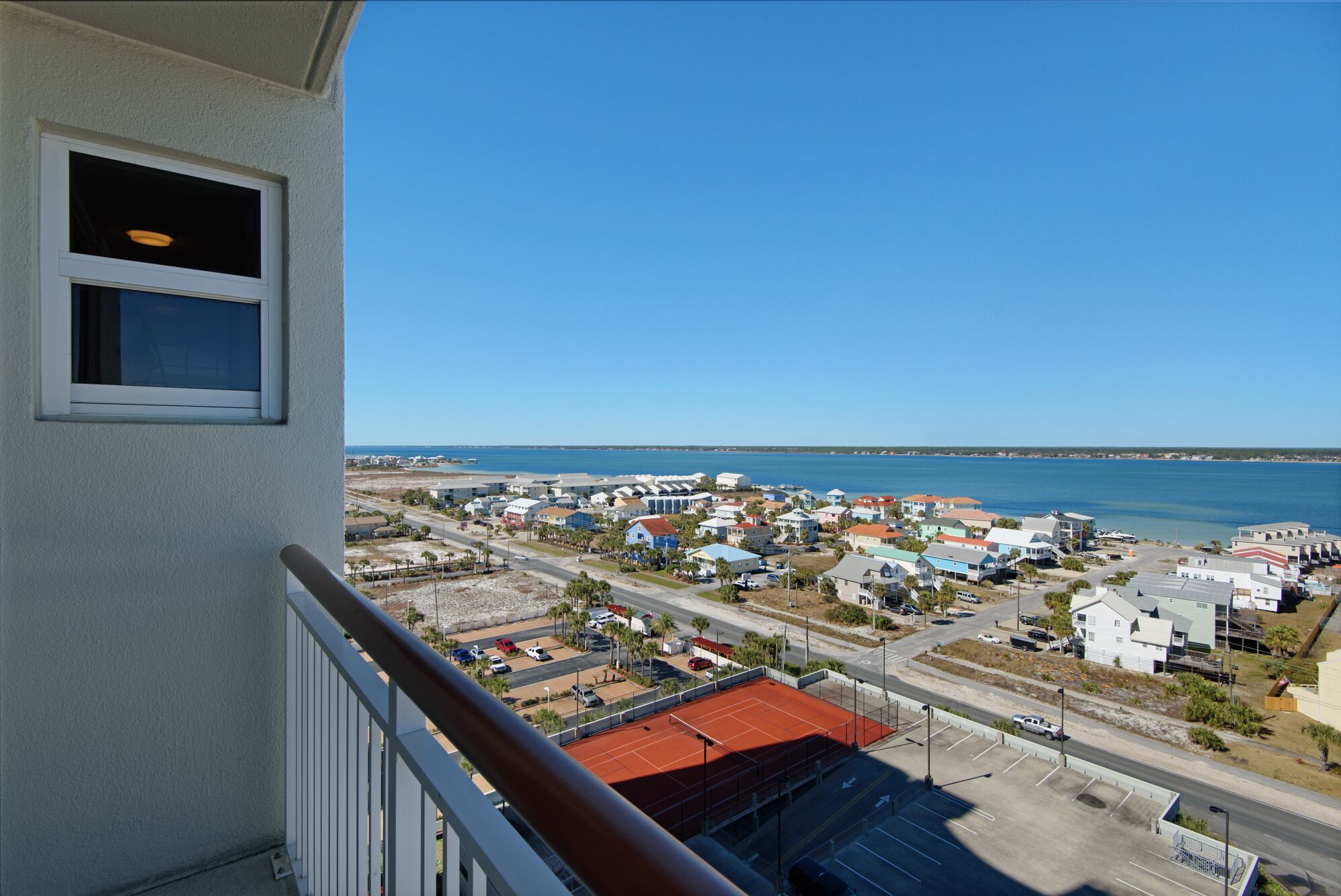 A coastal town with a mix of residential and commercial buildings, a clear blue sky, and a view of the sea.