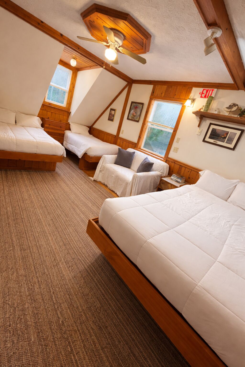 Una habitación con dos camas, un sofá, un ventilador de techo y una ventana con persianas.