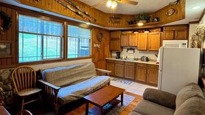 A cozy cabin-style interior with a wooden interior, a sofa, a dining table, and a kitchen area. - Beautiful Rustic 4 bdr Chalet Made For Big Groups and Life Long Memories! (Great Valley)