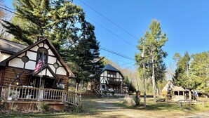 A traditional wooden building with a balcony and a flag, surrounded by trees and a clear sky. - Beautiful Rustic 4 bdr Chalet Made For Big Groups and Life Long Memories! (Great Valley)