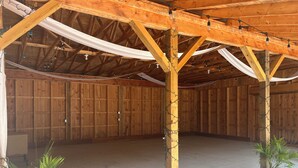 A spacious barn with wooden beams and a high ceiling, featuring a concrete floor and two potted plants. - Beautiful Rustic 4 bdr Chalet Made For Big Groups and Life Long Memories! (Great Valley)
