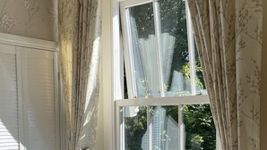 A room with a large window, a radiator, a grey chair, and a white wardrobe. - Newly refurbished 2 bedroom, 2 bathroom apartment right in the heart of Grasmere (Grasmere)