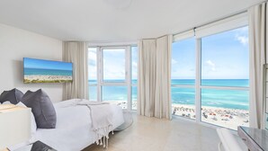 A hotel room with a large bed, a TV, and a view of the beach. - Oceanfront Private Condo at The Setai -2208 (Miami Beach)