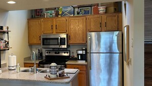 Une cuisine avec des meubles en bois, des appareils en acier inoxydable et une machine à café.