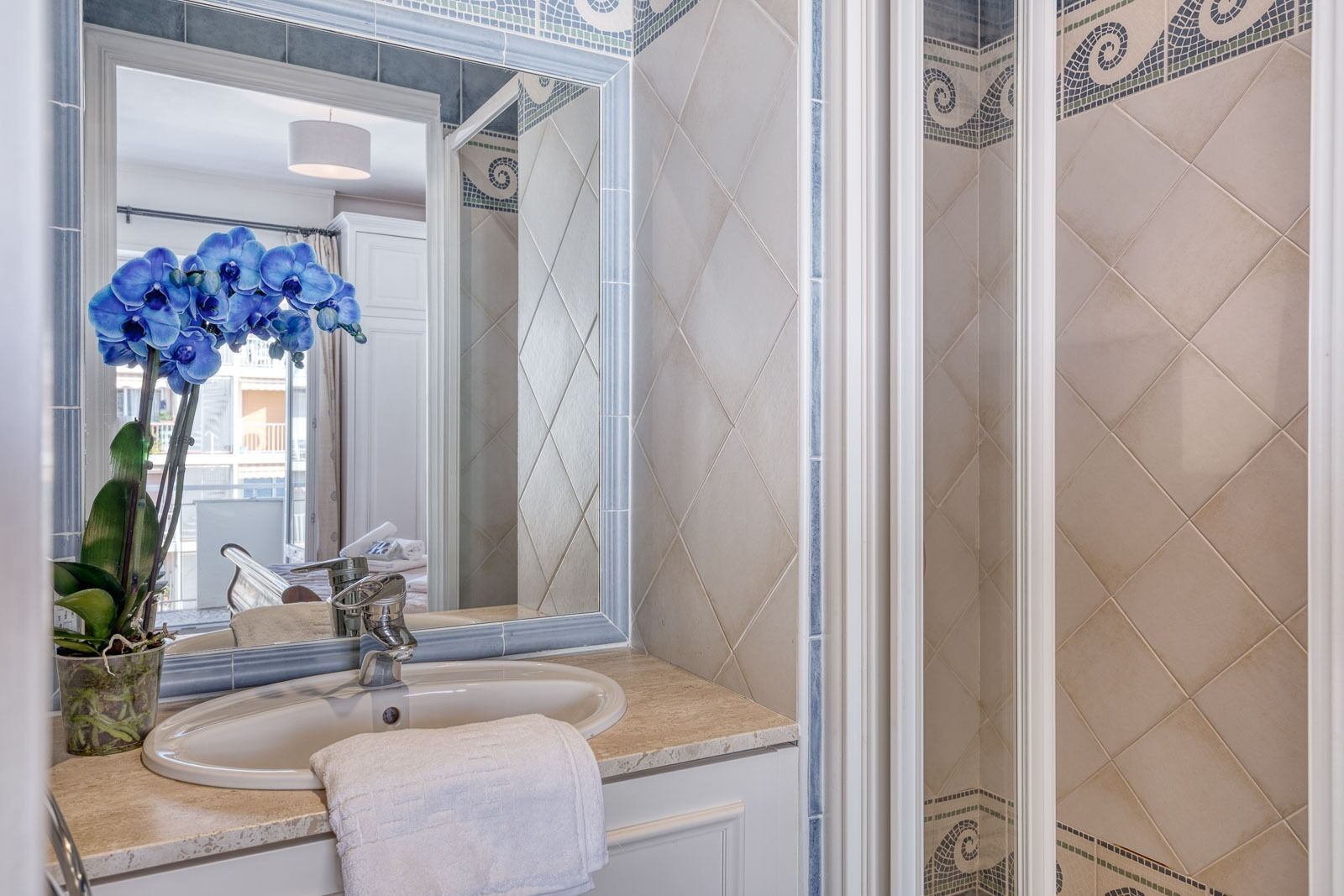 A bathroom with a sink, mirror, and shower area.