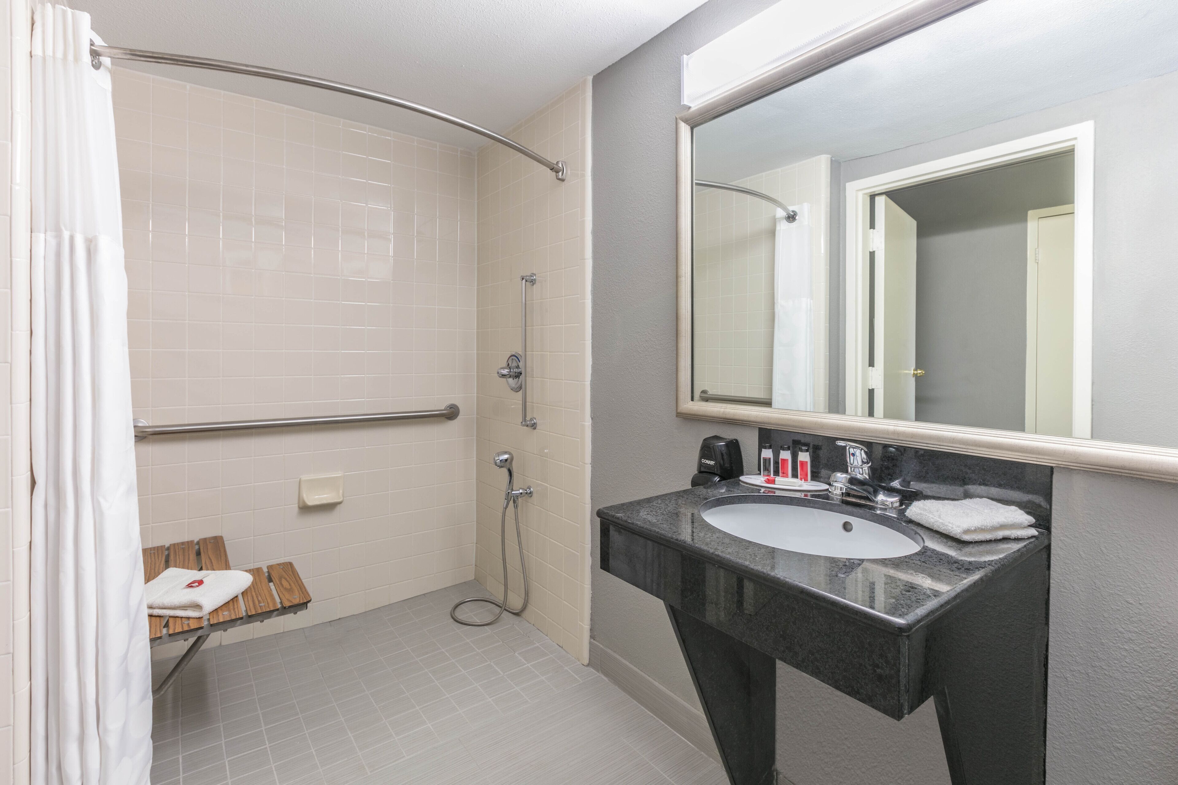 Une salle de bain avec une douche, un lavabo et un miroir.