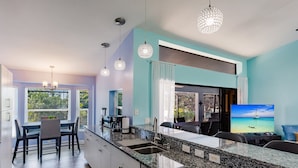 A modern kitchen with granite countertops, a built-in dishwasher, and a dining area with a table and chairs.