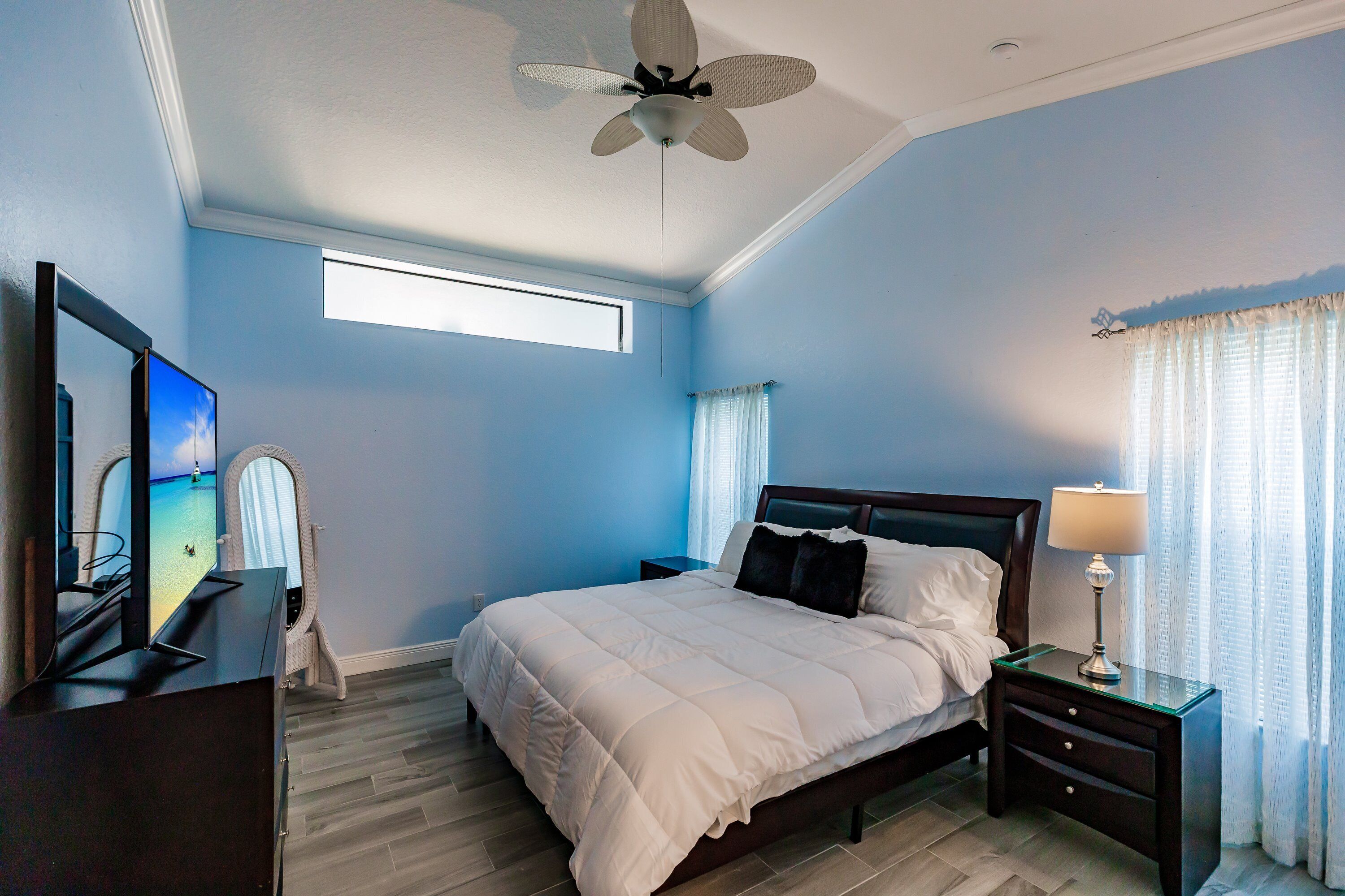 A bedroom with a bed, bedside table, lamp, and a ceiling fan.