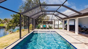 A covered swimming pool with a view of a lake and a patio area with outdoor furniture.