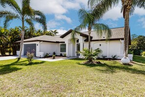A modern house with a well-maintained lawn and palm trees.