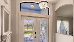 A double door with stained glass, a chandelier, and a view of the outdoors.