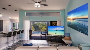 A modern living room with a TV, seating, and a view of the outdoors.