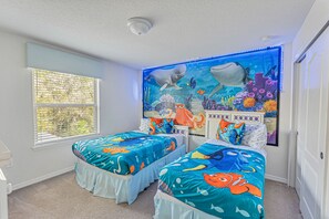 Quarto com duas camas, um mural grande de uma cena subaquática e uma janela com persianas.