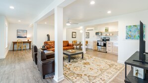 A spacious living area with a sofa, coffee table, and a rug. There is a kitchen area with modern appliances and a dining table. - Riverfront Oasis with Mountain Views, close to town  (Middletown)