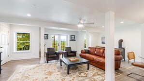 A spacious living room with a brown leather sofa, a coffee table, and a patterned rug. - Riverfront Oasis with Mountain Views, close to town  (Middletown)