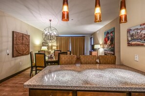 Habitación de hotel con una isla grande de granito, un comedor con candelabro y un cartel en la pared.