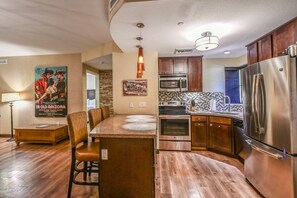 A compact kitchen with a central island, stainless steel appliances, and wooden cabinets.