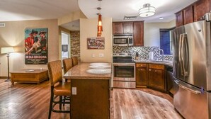 A compact kitchen with a central island, stainless steel appliances, and wooden cabinets.