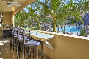 A balcony with a pool view, bar area, and outdoor seating. - Three Bedroom Condo Pool View, one block away from Medano Beach (Cabo San Lucas)