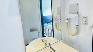 A modern bathroom with a large mirror, a white sink, and a visible ventilation system. - Ronsard (Bains-les-Bains)