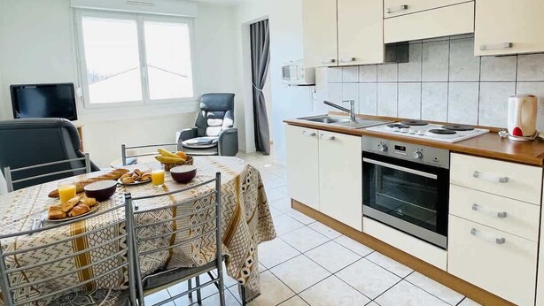 A modern kitchen with a dining area, a TV, and a window. - Ronsard (Bains-les-Bains)