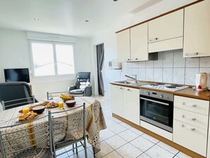 A modern kitchen with a dining area, a TV, and a window.