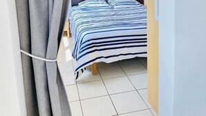 A bedroom with a bed, curtains, and a tiled floor. - Ronsard (Bains-les-Bains)