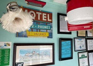 A wall with various signs and framed items, including a 'Motel' sign, a 'Vacancy' sign, and framed certificates. - RusMar Motel (Wildwood)